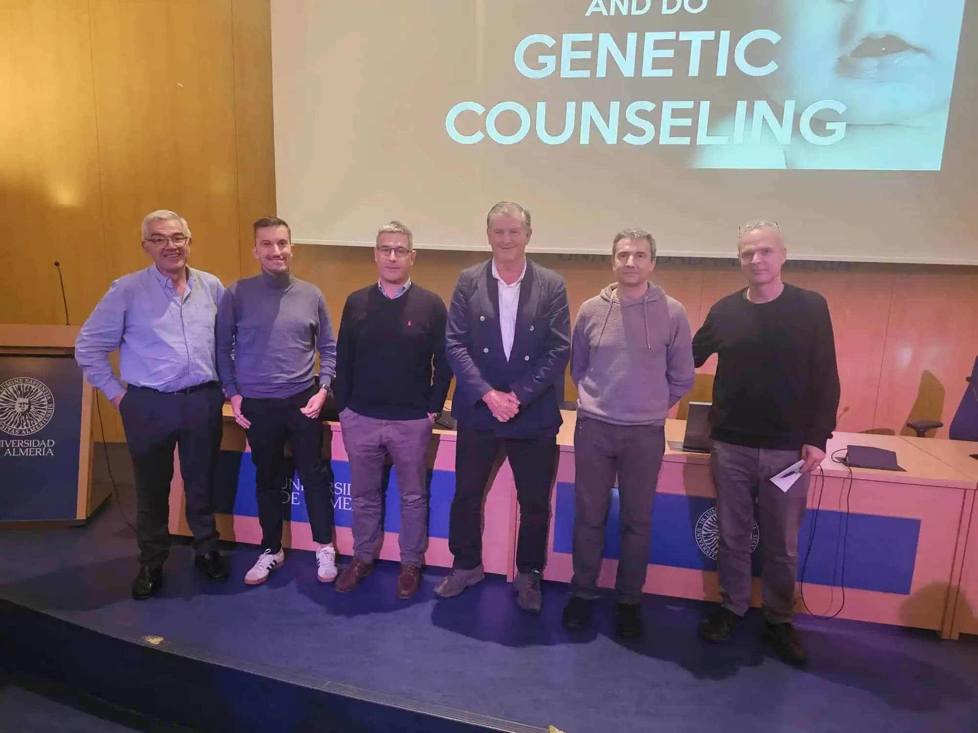 Los ponentes del congreso sobre NF1 en el escenario de la Universidad de Almería, con una diapositiva sobre consejo genético proyectada detrás